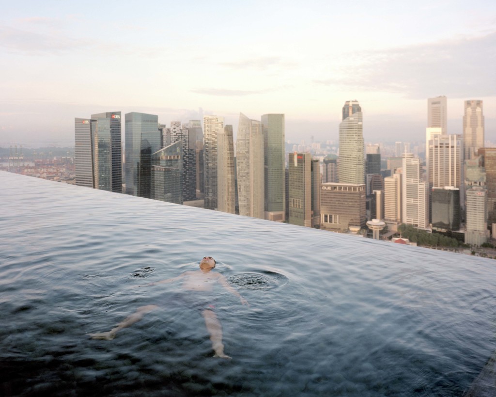 A man floats in the 57th-floor swimming pool of the Marina Bay Sands Hotel, with the skyline of “Central,” the Singapore financial district, behind him. Singapore