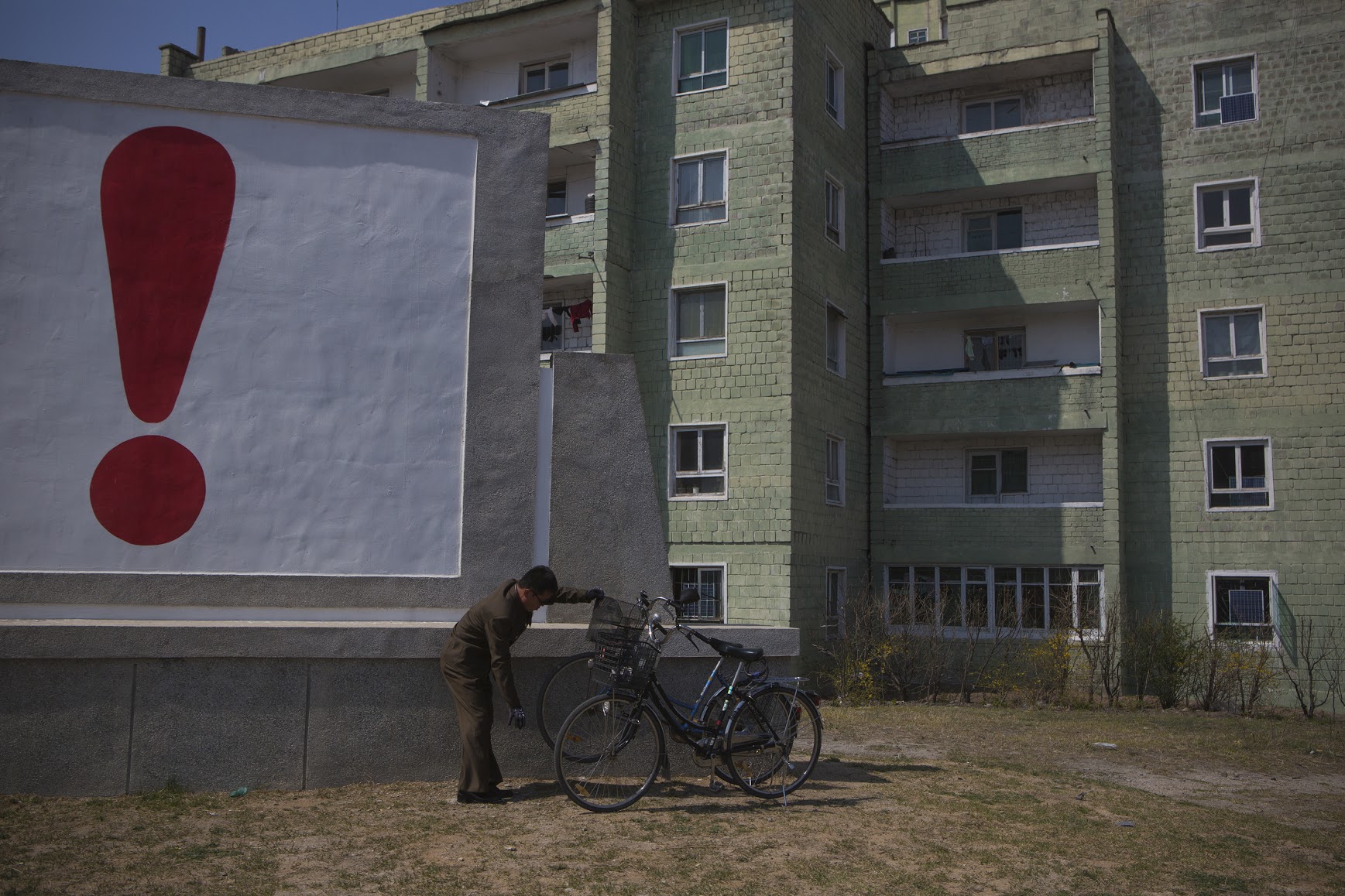 A North Korean man checks his bicycle next to a painted exclamation point on a propaganda billboard on Wednesday April 24, 2013 in Kaesong, North Korea, north of the demilitarized zone which separates the two Koreas.